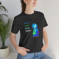 Blue Rescue, Foster, Adopt, Repeat Tee - Image of a female model standing in front of a green plant wearing a dark grey heather short sleeve jersey t-shirt with a multi-colored dog (terrier/mutt) head and chest looking up next to words in colors that match the dog - Rescue (blue) Foster (green) Adopt (teal) Repeat (white) 