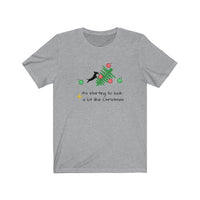 Tumbled Christmas Tree Unisex Jersey Tee - Heather Grey t-shirt with a picture of a line Christmas tree on it's side and a black silhouette dachshund jumping on the tree with several red and green ornaments falling off the tree