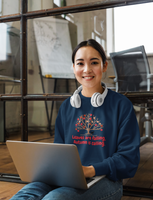 Image Description: Woman sitting on the floor with laptop and head phones wearing the navy crew neck sweatshirt.  The picture on the sweatshirt is a fall tree with red and orange and maple leaves with a black dog next to the tree and the phrase, "Leaves are falling. Autumn is calling." in red text